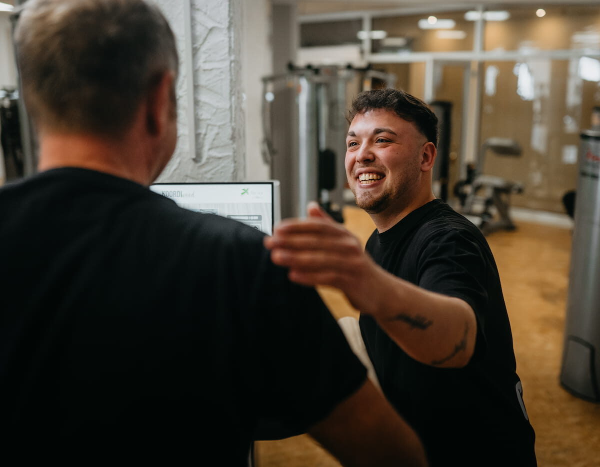 bonusprogramm Freundlicher Mitarbeiter im Fitnessstudio begrüßt einen Kunden